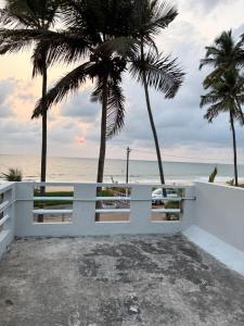 a white fence with palm trees in front of the beach at Mannath lands end Beach house in Kaup