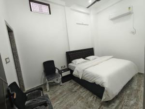 a white bedroom with a bed and a chair at Ma SAVITRI PALACE in Ayodhya