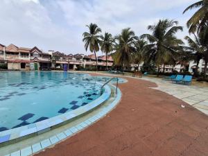 a large swimming pool with palm trees in a resort at Bliss Inn in Benaulim