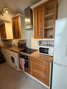 a kitchen with wooden cabinets and a white refrigerator at Flat 4 Rylands Street in Warrington