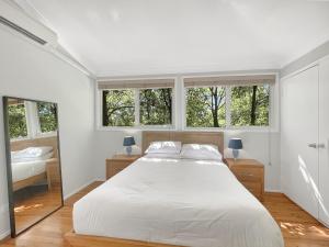 a white bedroom with a large bed and two windows at Riverside 3-Bed Townhouse with Spacious Deck in Mossy Point