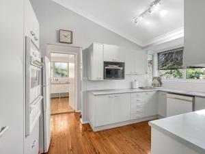 a white kitchen with white cabinets and a refrigerator at Riverside 3-Bed Townhouse with Spacious Deck in Mossy Point