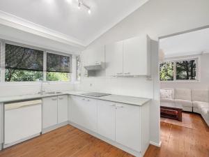 a white kitchen with white cabinets and a couch at Riverside 3-Bed Townhouse with Spacious Deck in Mossy Point +23 photos