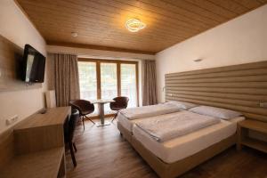 a bedroom with a bed and a desk and a television at Hotel Bergland in Sillian