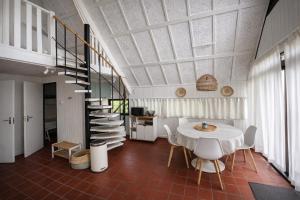 a dining room with a table and a spiral staircase at De Vlier 8* in Nieuwvliet
