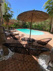 a table and chairs with an umbrella in front of a pool at Villa Marrakech ,Piscine Privée & Luxe Authentique in El Aggada