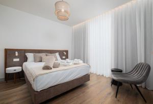 a bedroom with a large bed and a chair at Mónaco Suites & Garden in Ponta Delgada