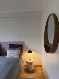 a bedroom with a bed and a round mirror at Aqui na Praia do Pedrogão in Leiria
