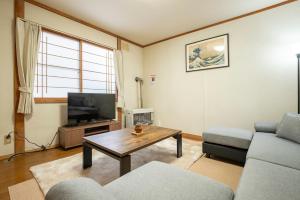 a living room with a couch and a tv at Otaru Retro Villa in Otaru