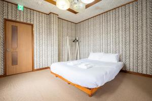 a bedroom with a large bed with white sheets at Otaru Retro Villa in Otaru +70 photos
