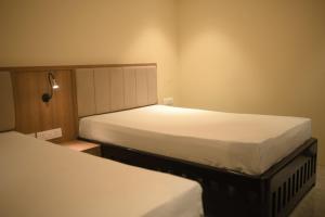a bedroom with two beds with white sheets at Mahamaya Hotel in Gohpur