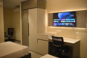 a room with a desk and a tv on the wall at Mahamaya Hotel in Gohpur