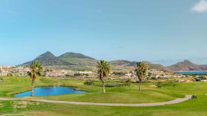 a golf course with palm trees and a pond at Casa Sol e Praia in Porto Santo