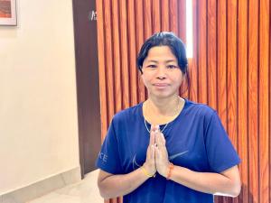 a woman in a blue shirt praying in front of a curtain at Sky Heritage Hotel in Phnom Penh