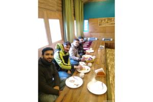 a group of people sitting at a table eating food at Thrillomania Kasol in Kasol