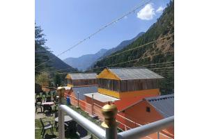 a group of buildings with mountains in the background at Thrillomania Kasol in Kasol