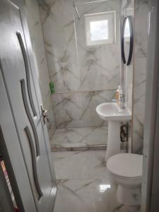 a white bathroom with a toilet and a sink at Apartament in Geoagiu Băi
