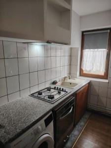 a kitchen with a stove top oven next to a sink at Apartament in Geoagiu Băi