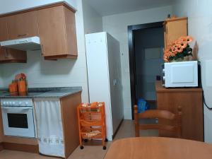 a small kitchen with a refrigerator and a kitchen table at Apartamento Ria de Vegadeo in Vegadeo