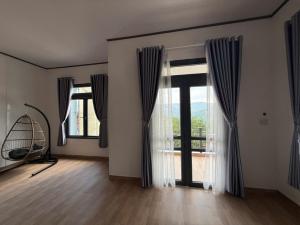 a living room with large windows and a wooden floor at Mây's Villa in Da Lat
