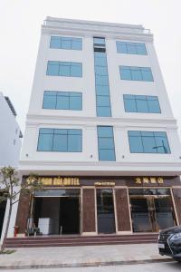 a tall white building with windows on a street at Long Hải Hotel in Móng Cái