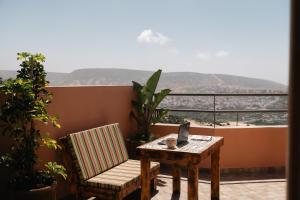 a table and a chair on a balcony with a view at Tasga Guest House in Tamraght Ou Fella