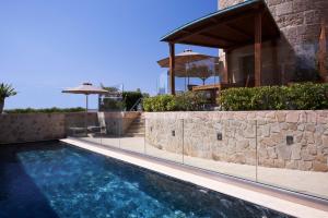 a swimming pool in front of a house with a stone wall at Bellevue On The Beach Suites in Rhodes Town +41 photos