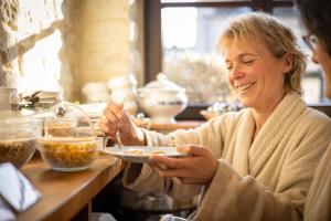 a woman sitting at a table eating a plate of food at Thermae Boetfort Hotel in Steenokkerzeel