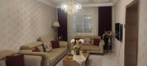 a living room with couches and a chandelier at Maison du Bonheur in Ariana