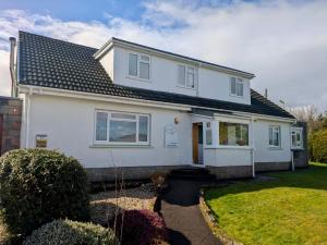 a white house with a black roof at The Otter Lodge in Broadford