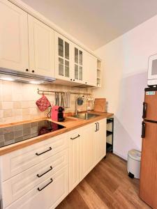 a kitchen with white cabinets and a sink and a refrigerator at Locanda dei Gelsomini in Civitella Del Lago