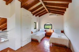 two beds in a room with white walls and wooden ceilings at Villa Anna Maria by Villa Plus in Pírgos Psilonérou +11 photos