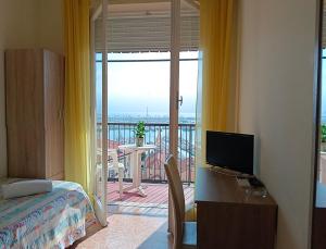 a bedroom with a bed and a desk with a television at Hotel Robinia in Imperia