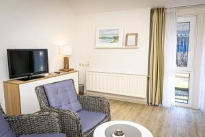 a living room with a chair and a tv at FineApartment Alt Duvenstedt in Alt Duvenstedt