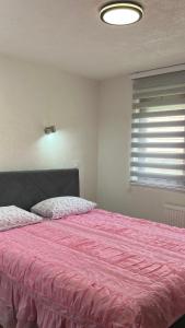 a bedroom with a large bed with a pink blanket at Behar Apartment with City View in Sarajevo