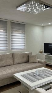 a living room with a couch and a tv at Behar Apartment with City View in Sarajevo