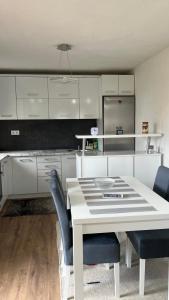 a kitchen with a white table and chairs and cabinets at Behar Apartment with City View in Sarajevo