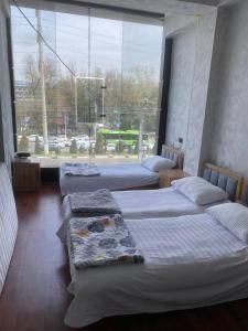 three beds in a room with a large window at Best hotel in Yakkasaray
