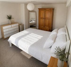 a bedroom with a white bed with a dresser and a mirror at Westbrook Spacious 3 Bed in Exeter in Pinhoe