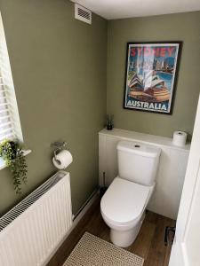 a bathroom with a toilet and a poster on the wall at Westbrook Spacious 3 Bed in Exeter in Pinhoe