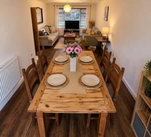 a wooden table with plates and flowers in a living room at Westbrook Spacious 3 Bed in Exeter in Pinhoe +4 photos