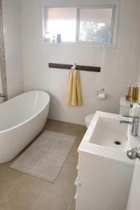a white bathroom with a tub and a sink at Poolside on the Plateau in Wollongbar