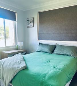 a bedroom with a green bed with a large window at Poolside on the Plateau in Wollongbar