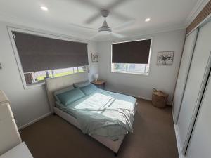a bedroom with a bed and two windows at Poolside on the Plateau in Wollongbar +2 photos