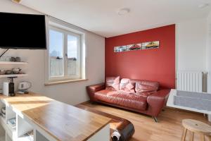 a living room with a couch and a red wall at SleutelVan8 in Knokke-Heist
