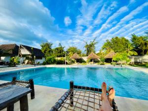 a person laying on a bed in front of a swimming pool at Apartments Maliki, Matemwe in Matemwe