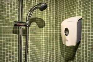 una doccia in un bagno piastrellato verde con un distributore di sapone di Y Loft a Hong Kong Altre 29 foto