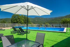 a table with an umbrella next to a swimming pool at Apartmani Maja in Rastište