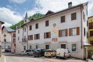 a white building with cars parked in front of it at Edelweiss Alp Rooms in Castello Tesino
