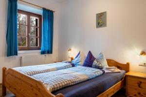 a bedroom with two beds with blue curtains and a window at Sallrain Hof Apartment 1 in Collalbo
